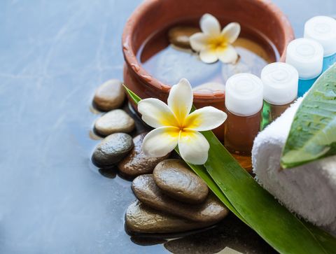 Massagesteine, Aromaöle und Blüten in warmem Licht